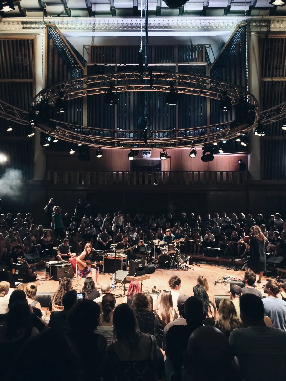 Funkhaus Berlin's Saal 1 set up in the round for PEOPLE — a ring truss of lights hung beneath the organ pipes, musicians on a floor stage surrounded by the audience on all sides